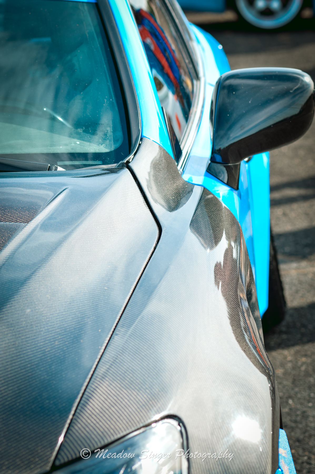 A carbon fibre fender beside a bright blue car