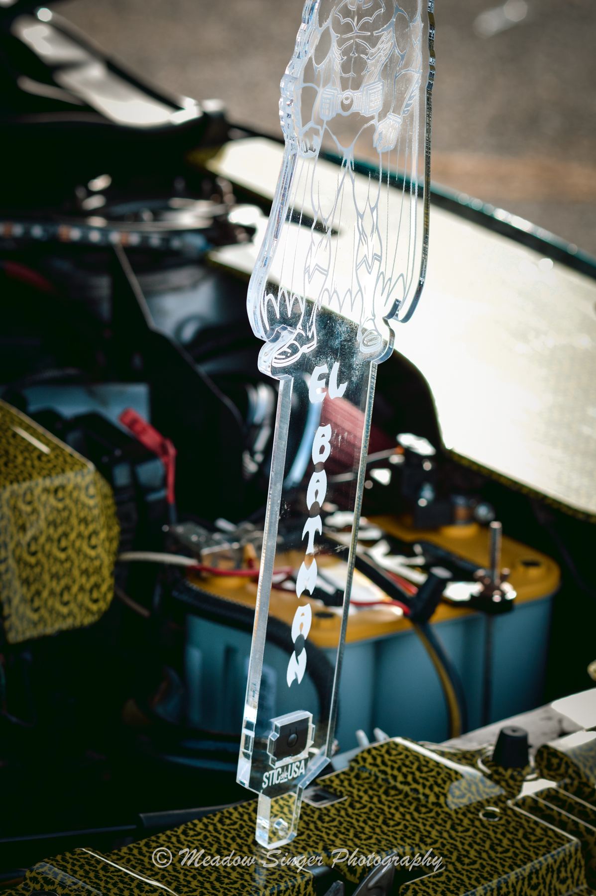 A clear acrylic Batman piece standing in an engine bay