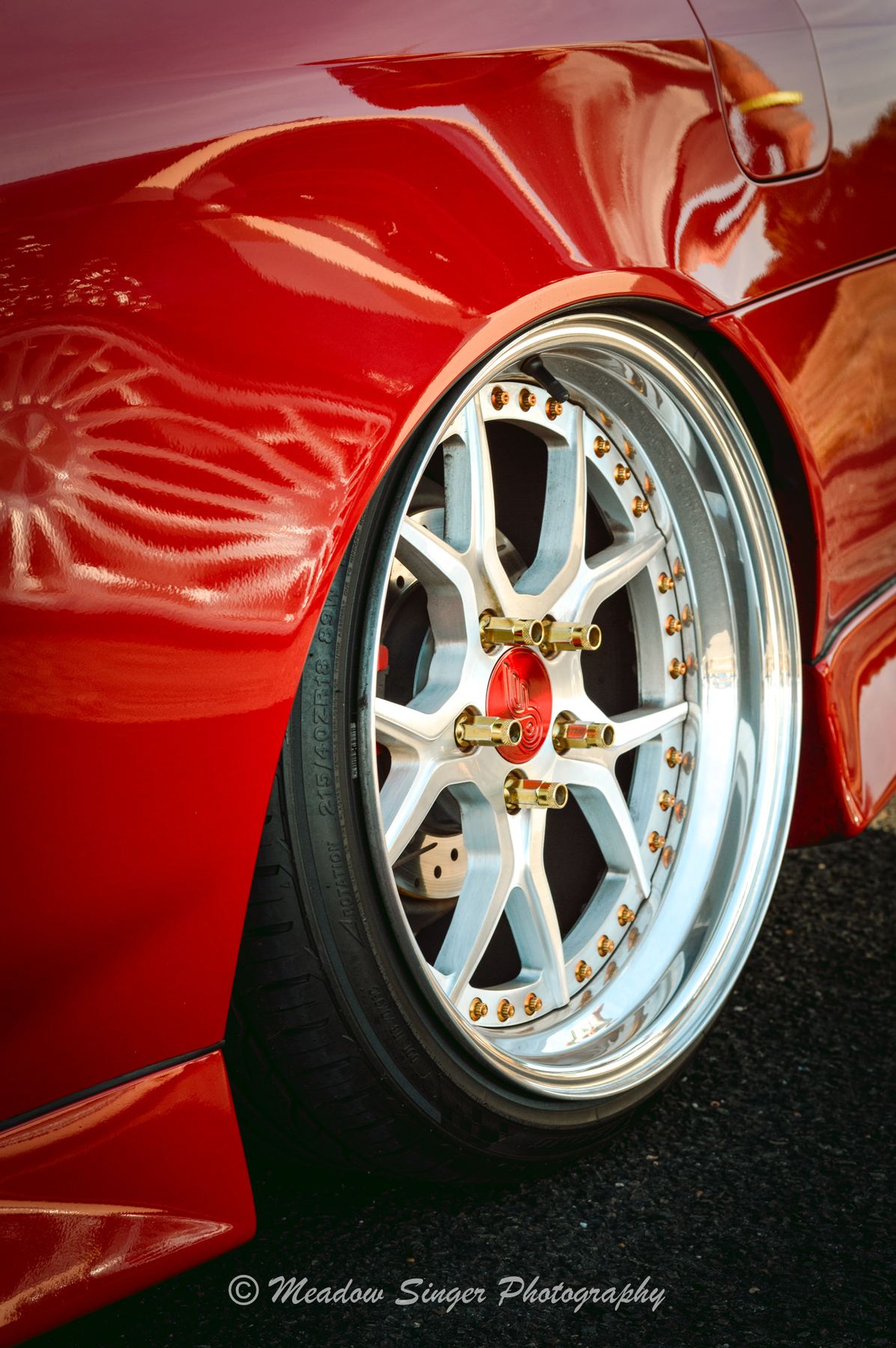 A gold centred wheel on a deep red show car