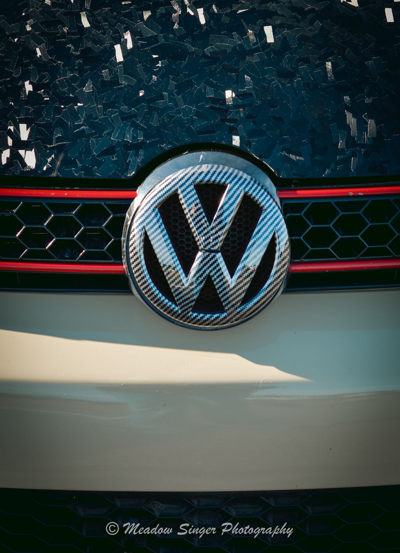 A carbon fibre Volkswagen badge on a grille