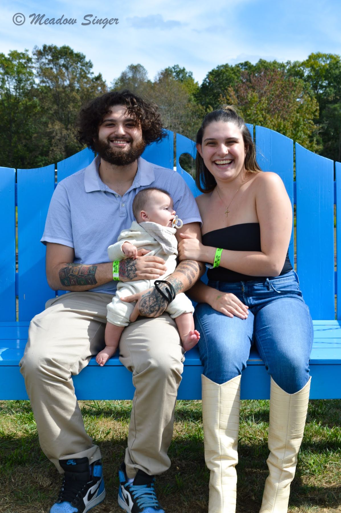 Young parents with their baby on a bright blue bench
