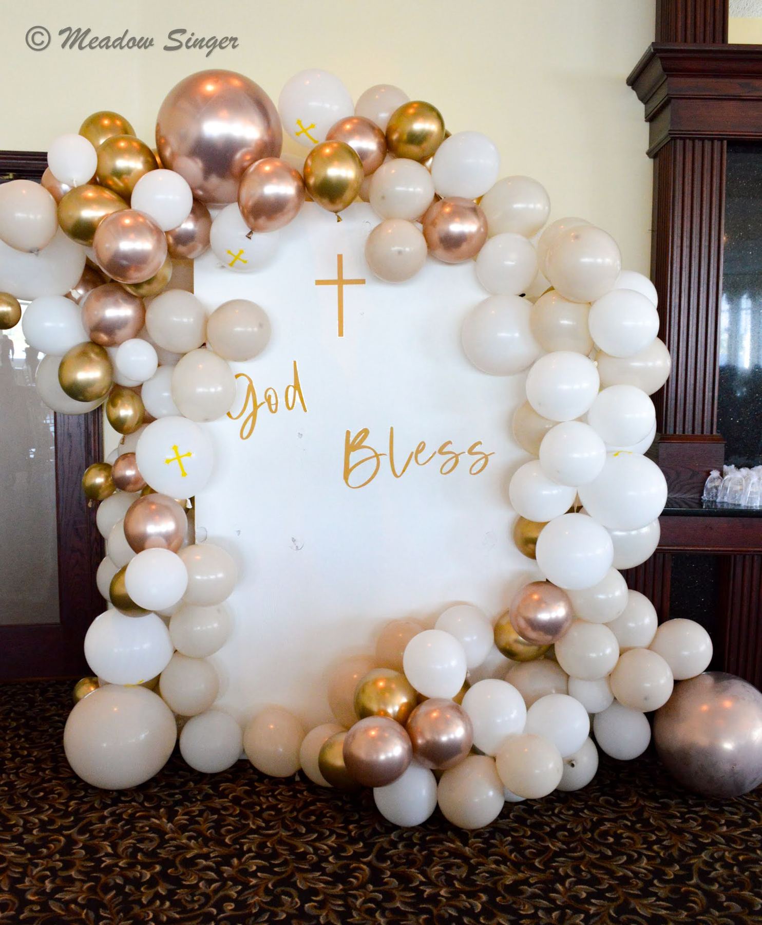 A God Bless sign framed by white and gold balloons