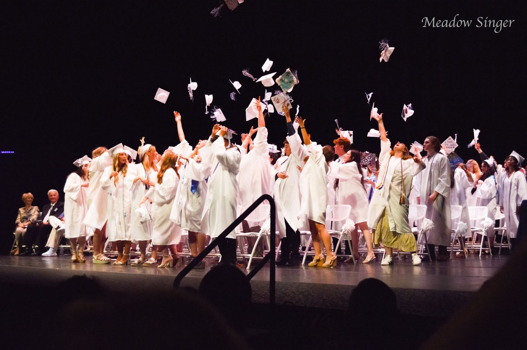 Graduates throwing their caps in the air on a stage